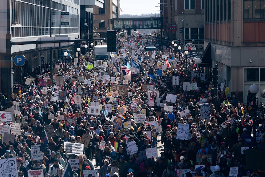 Huge crowds seen marching to the State Capitol in Minnesota, many of which are holding up banners.