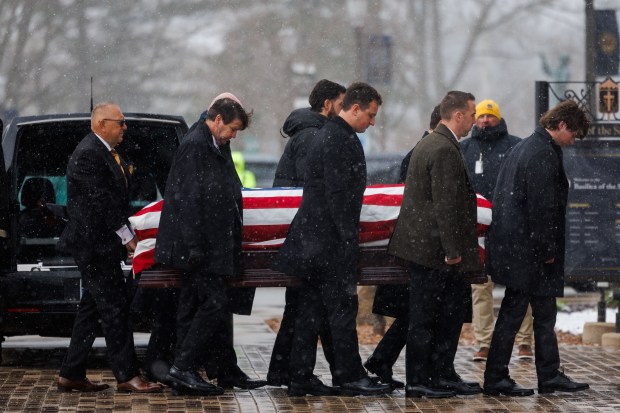 A flag drapes over the casket for former Notre Dame football coach Lou Holtz while being carried into the Basilica of the Sacred Heart at Notre Dame on March 16, 2026, in South Bend, Indiana. (Armando L. Sanchez/Chicago Tribune)