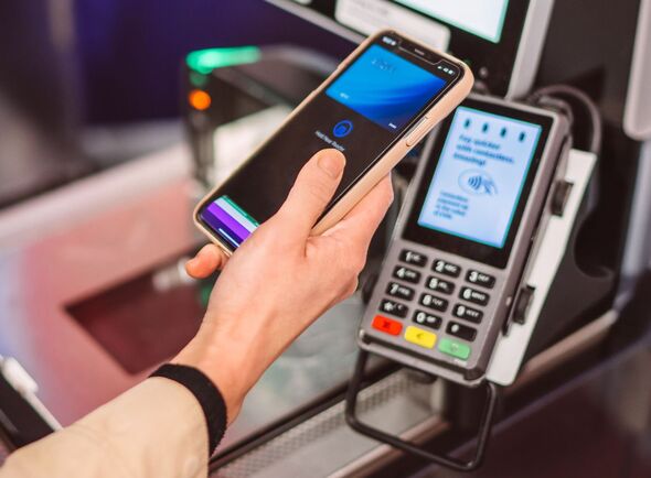 Customer using smart phone for contactless payment at supermarket self checkout Customer using smart phone for contactless payment at supermarket self checkout