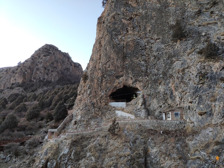 A cave entrance in a mountain landscape.