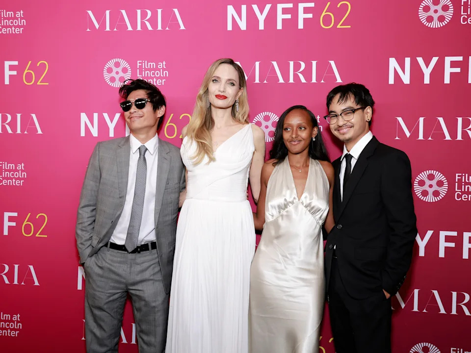 Four people in formal attire pose for a photo at a red carpet event with "NYFF62" and "Maria" signage in the background