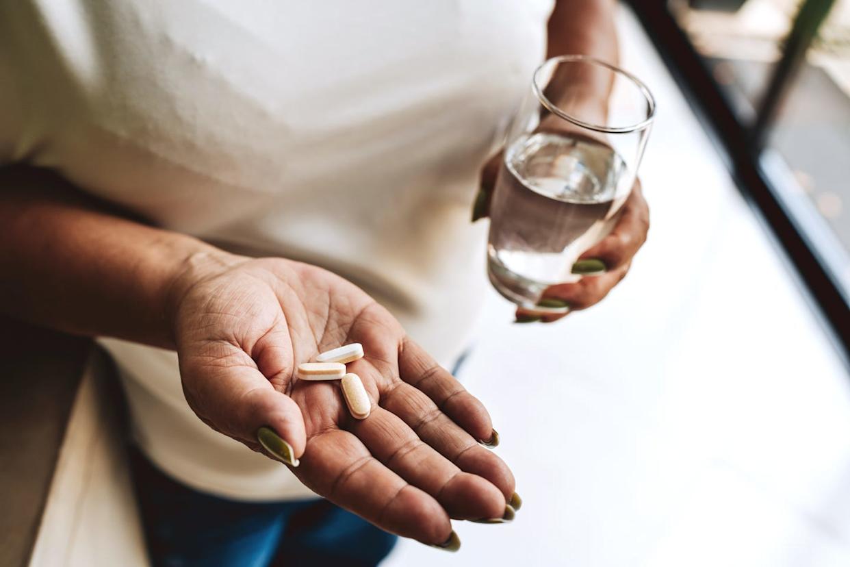 Senior woman self-medicating with medicine at home, unrecognizable person