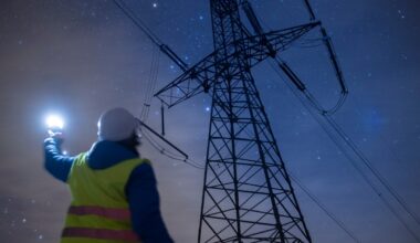 High-voltage engineer working on power lines at night.
