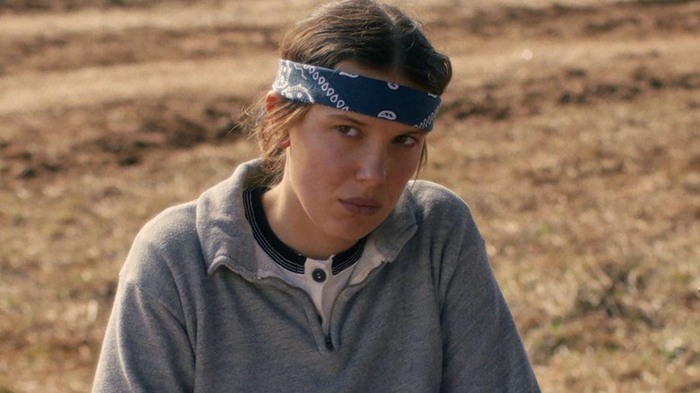 Millie Bobby Brown as Eleven in a sweatshirt and wearing a headband in Stranger Things