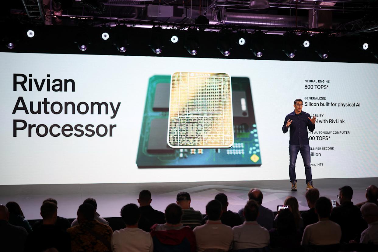 Rivian CEO RJ Scaringe speaks as a screen displays a visualization of Rivian's Autonomy processor, at the company's first Autonomy and AI Day, showcasing developments in self-driving technology, in Palo Alto, Calif., on Dec. 11, 2025. (Reuters/Carlos Barria)