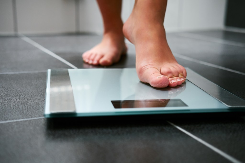 A person's bare feet stand on a bathroom scale.