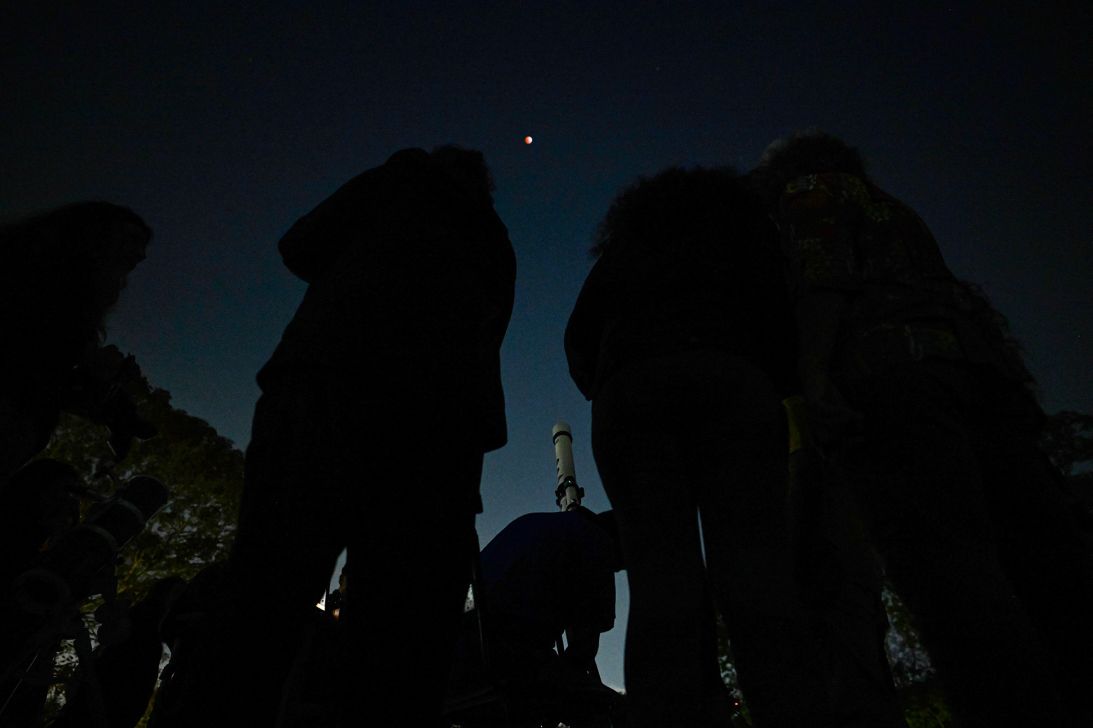 People gather near a telescope to watch the full blood moon in Caracas, Venezuela, in March 2025.