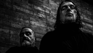 Studio promotional photo of Godflesh featuring members Justin Broadrick and G. C. Green posed against a dark industrial backdrop.