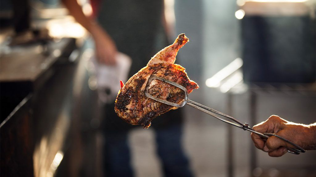 grilled chicken meat held with tongs