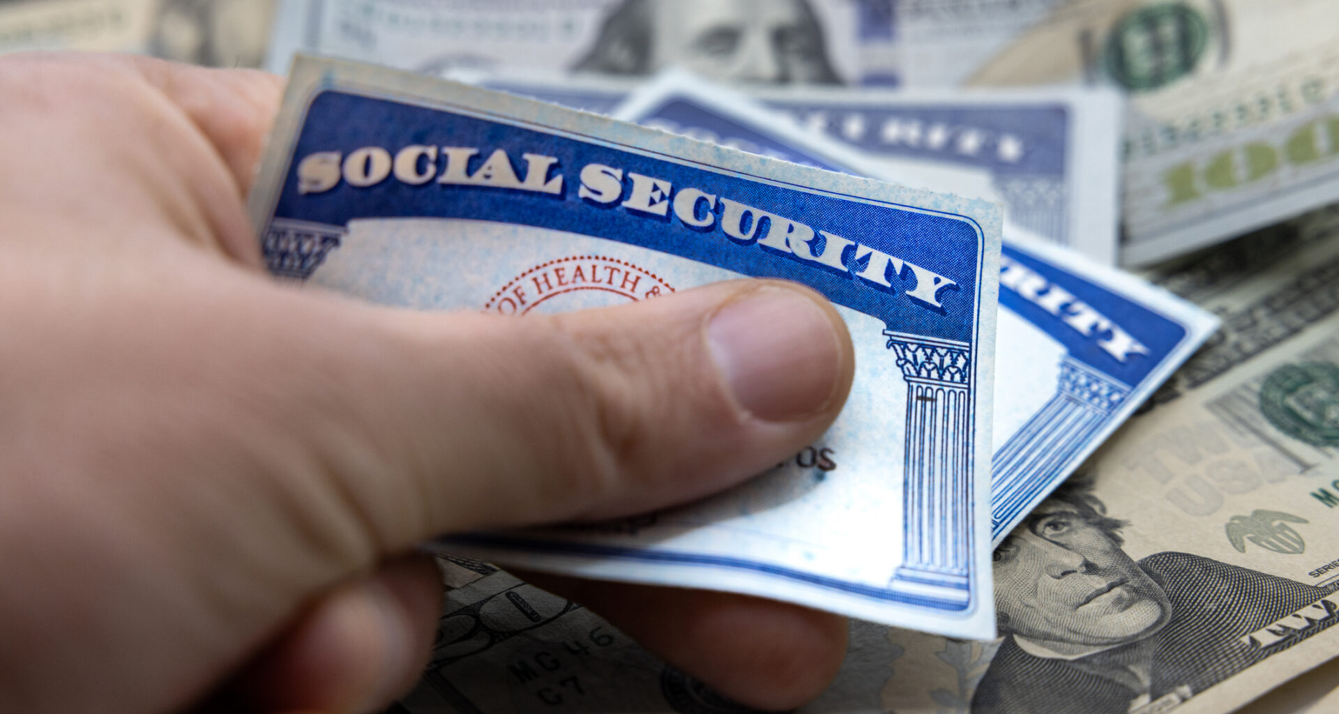 Male hand placing Social Security cards over American dollars