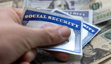 Male hand placing Social Security cards over American dollars