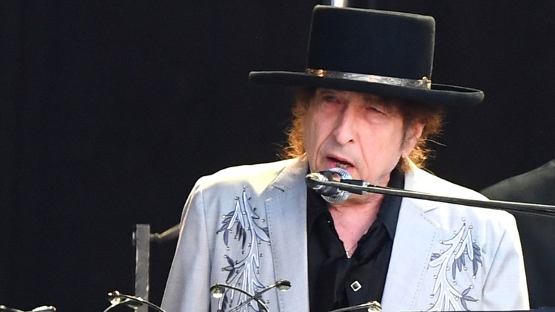Bob Dylan performing on stage, wearing a black brimmed hat.
