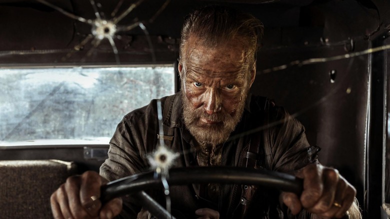 Jorma Tommila as Aatami Korpi in the cab of his bullet-riddled truck in Sisu: Road to Revenge