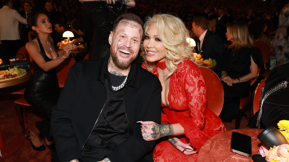 Jelly Roll and Bunnie Xo standing together on a red carpet at the Grammy Awards.