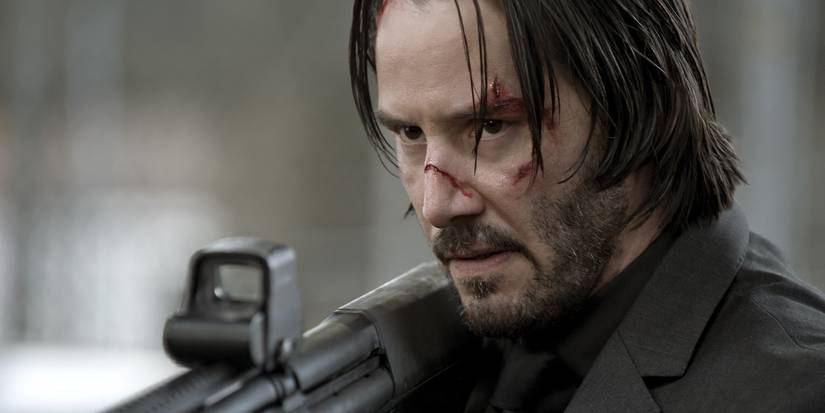 Keanu Reeves as John Wick aiming a rifle in John Wick (2014)