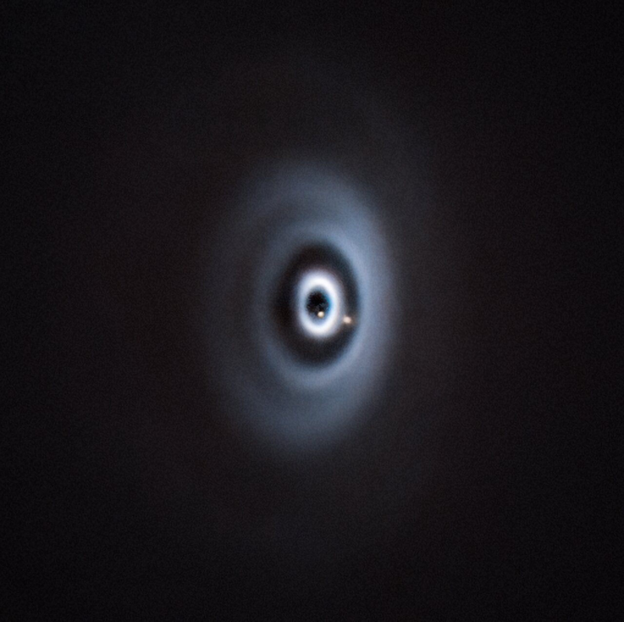 Concentric gray wispy rings have two glowing dots stashed within.