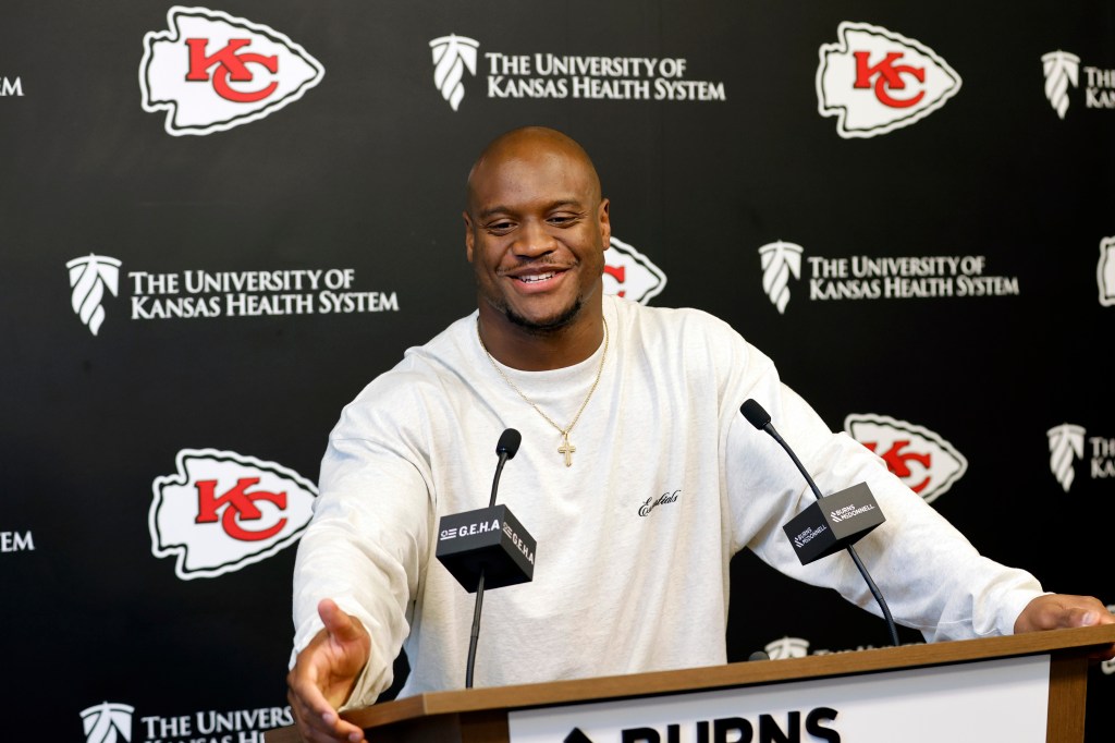 Kenneth Walker III smiling at a press conference with Kansas City Chiefs and University of Kansas Health System logos in the background.