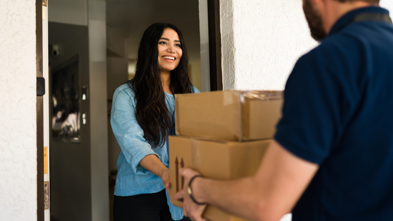 women handing multiple packages to a delivery person