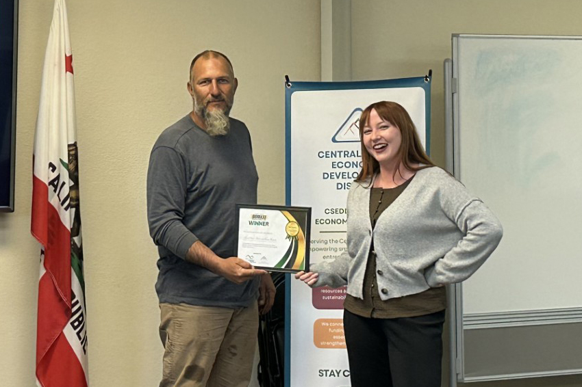 (left to right) RJ Skaar being presented the microgrant by Sophia Kaufman, who organized the event—Central Sierra Biomass Business Competition photo