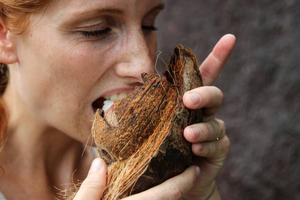 A woman smelling a large, decayed piece of wood or tree bark.