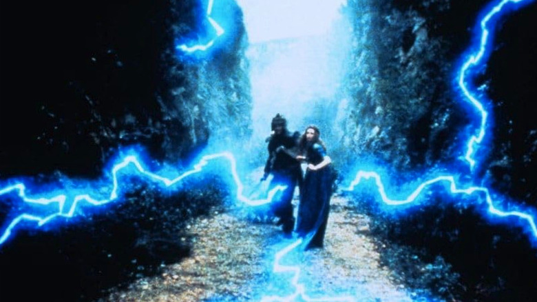 Liam Neeson's Grak and Rosalyn Landor's Guinevere stand amid blue lightning in  Merlin and the Sword