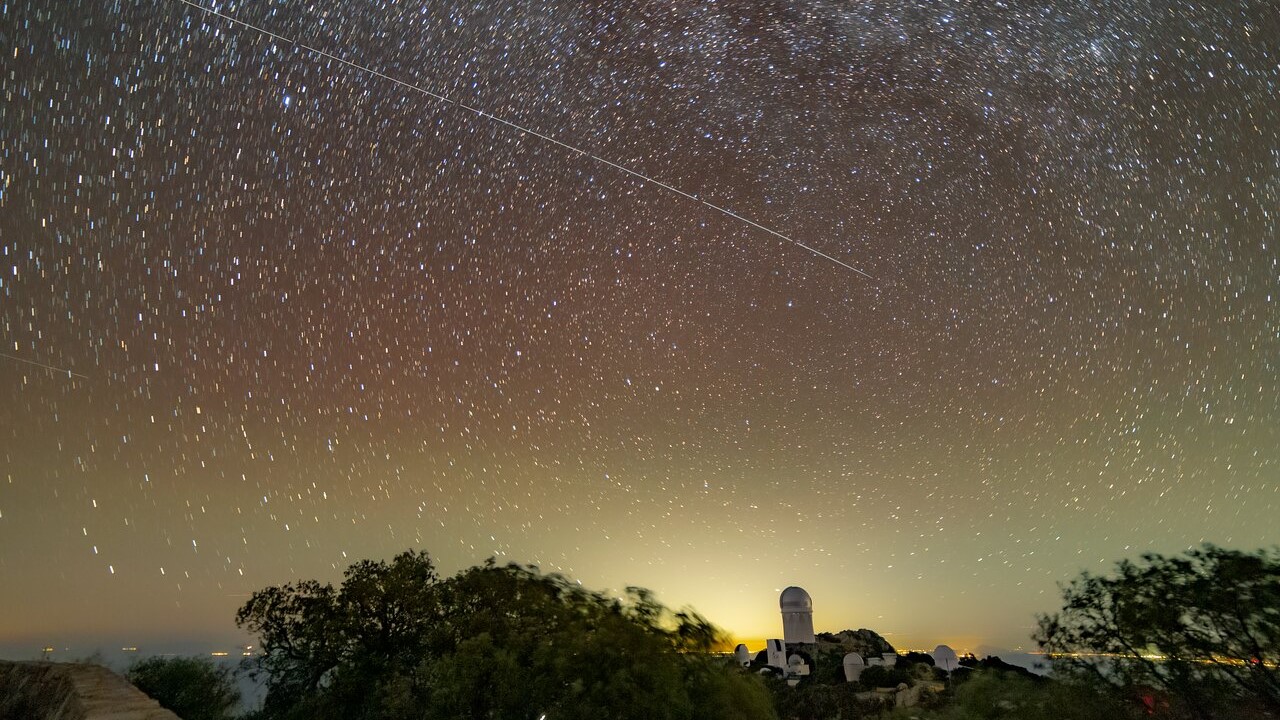 A view of the starry sky with a bright white streak across it.