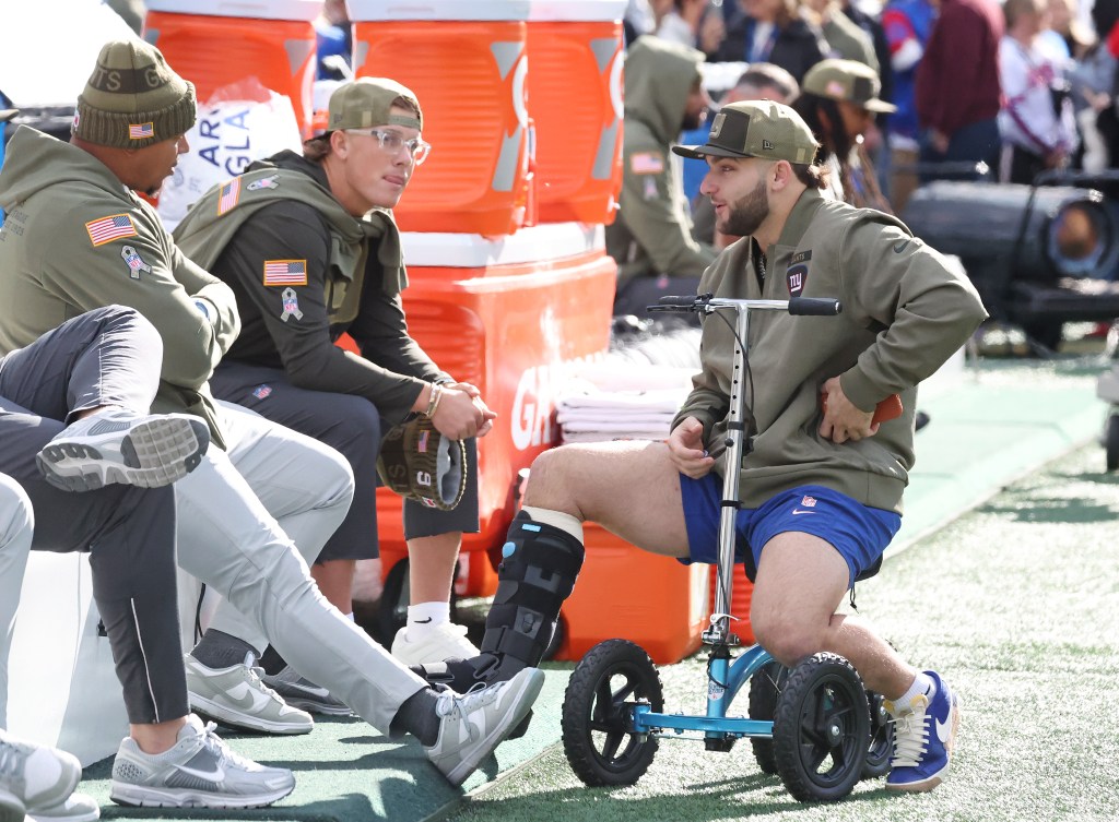 New York Giants quarterback Jaxson Dart and running back Cam Skattebo chat before a game.