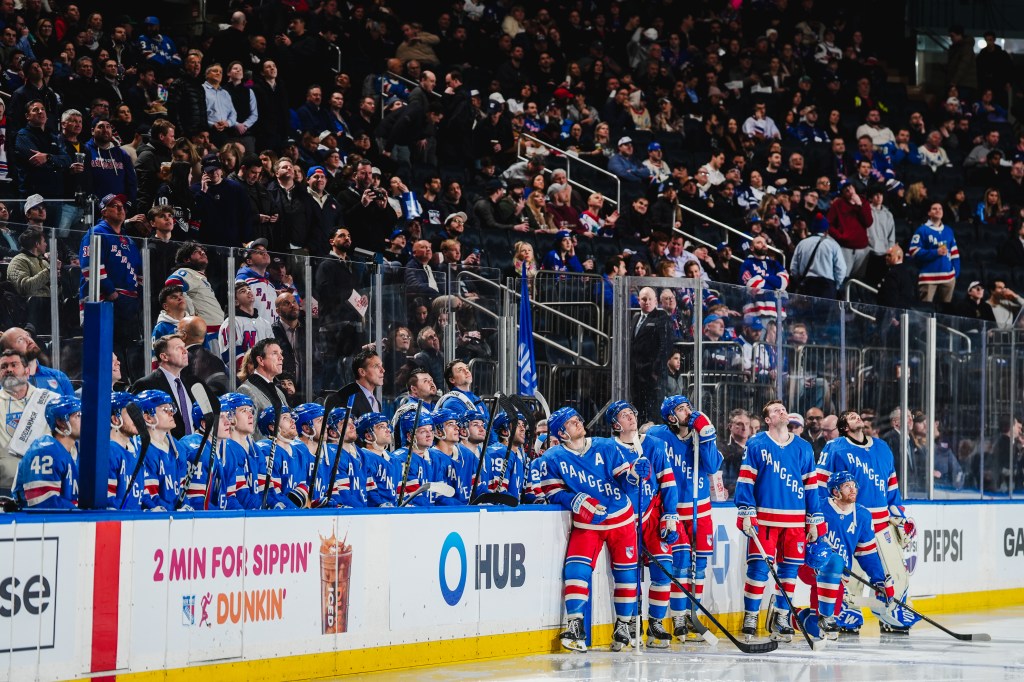 New York Rangers players on the bench looking up during a game.