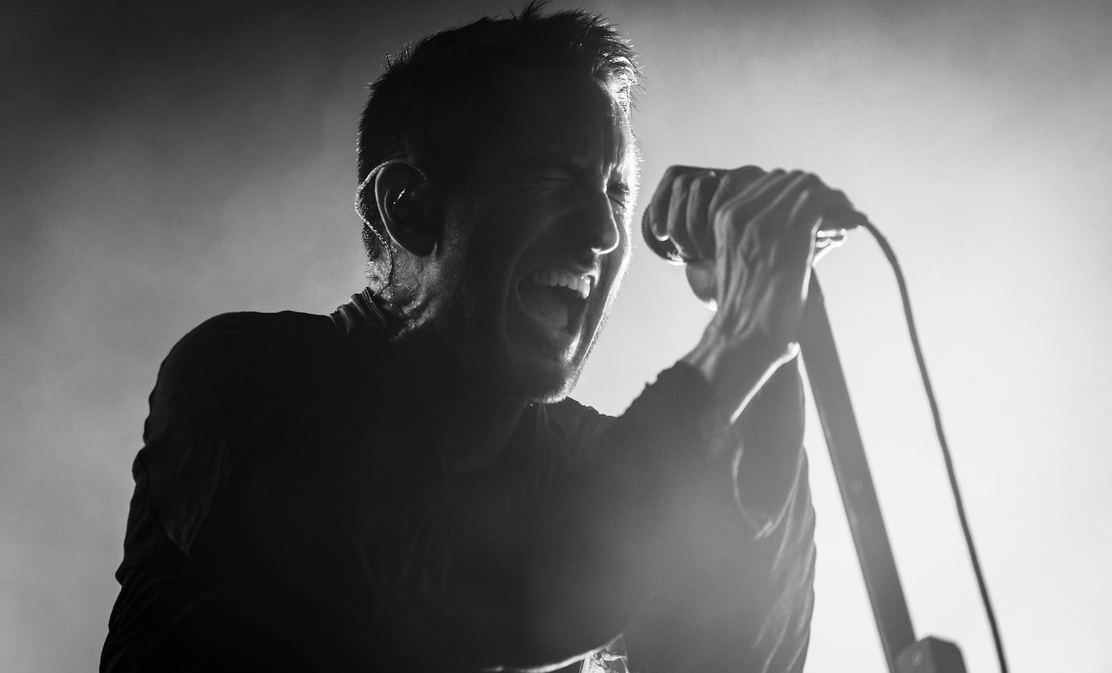 Trent Reznor performing live on stage with Nine Inch Nails during a concert.