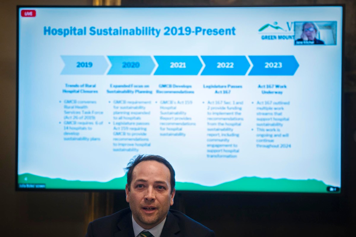 A man is standing in front of a tv screen with the words hospital sustainability 2019 present.