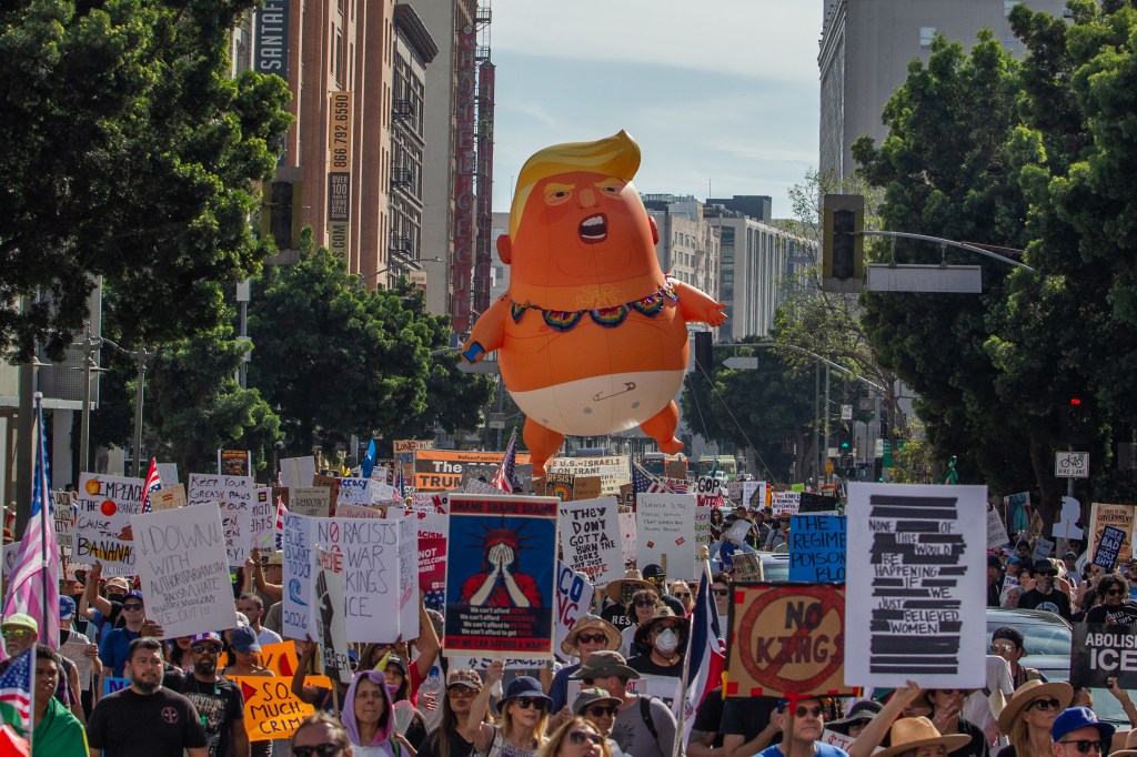 People protest immigration enforcement and federal overreach, featuring a large balloon of Trump in a diaper.
