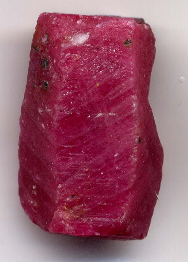 Oblong, somewhat rectangular rough irregular red crystal.