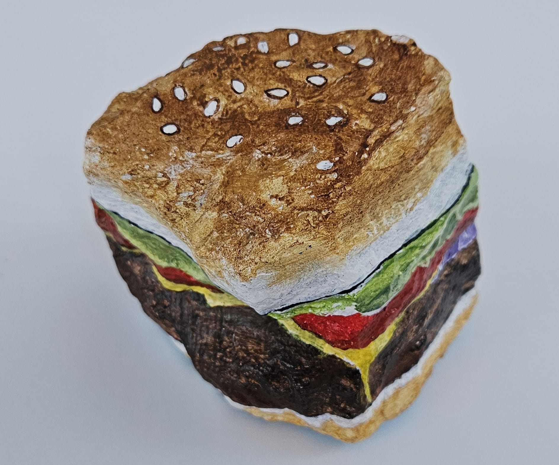 A painted rock by Elizabeth Saloka that resembles a hamburger