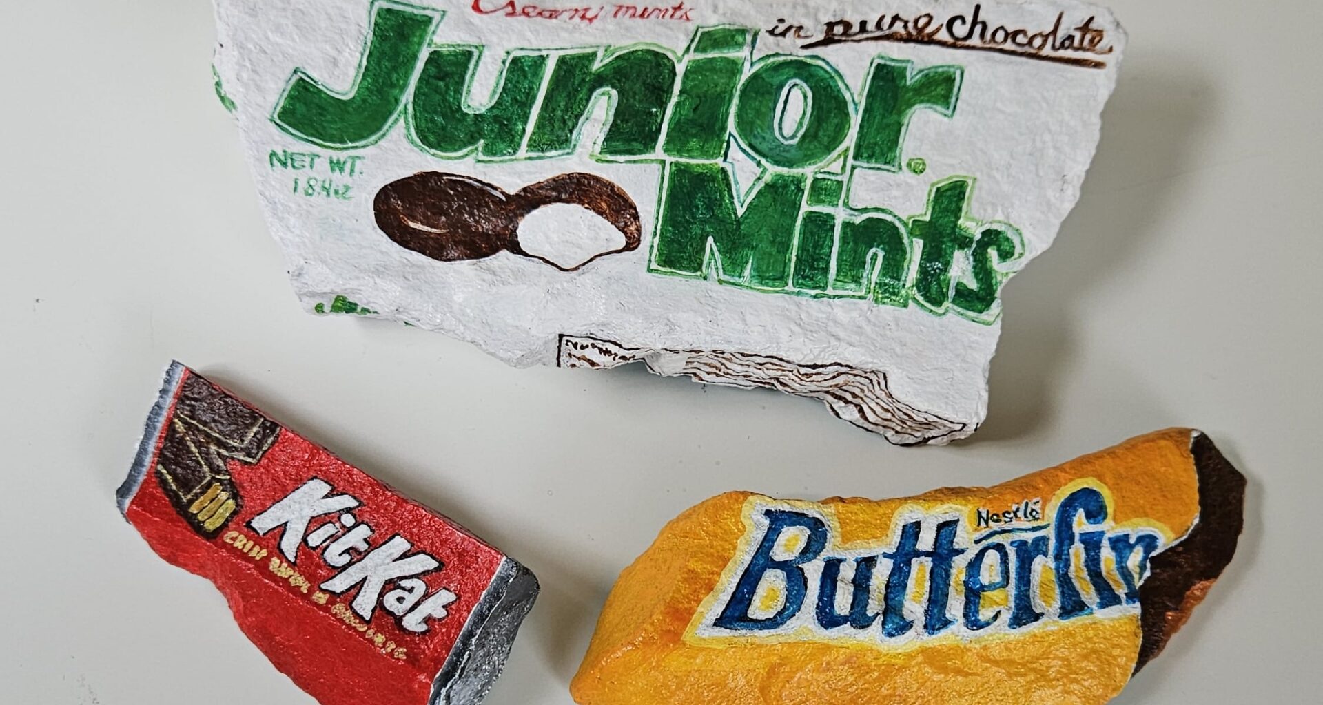 Painted rocks by Elizabeth Saloka that resemble Butterfinger, Kit Kat, and Junior Mints candies
