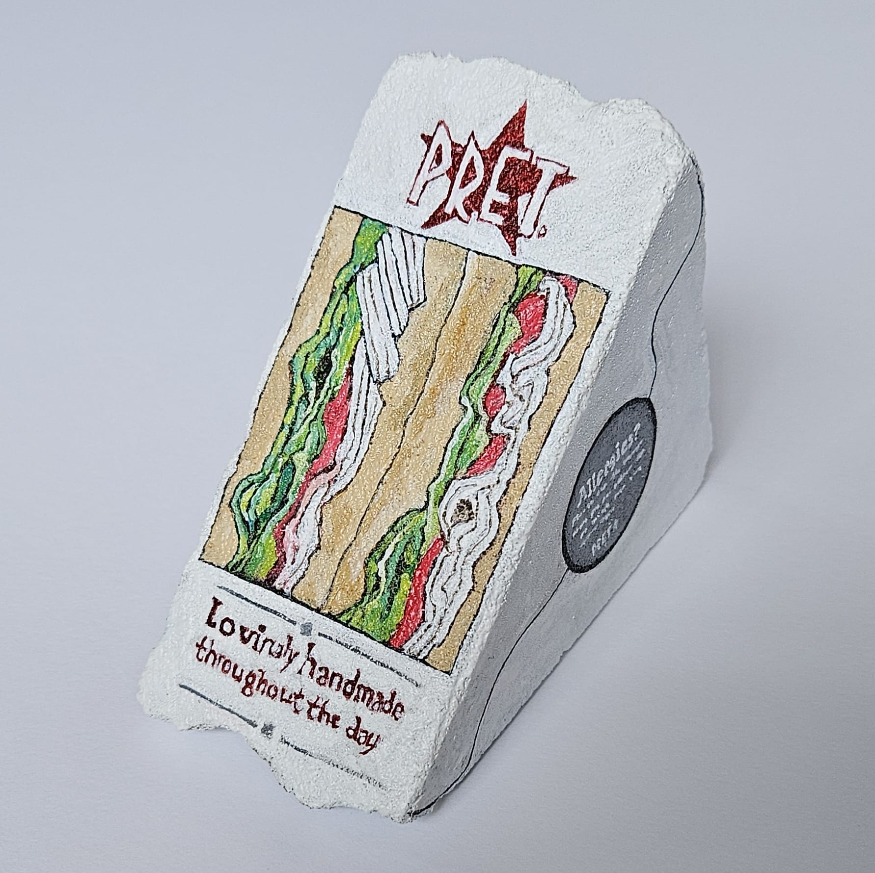 A painted rock by Elizabeth Saloka that resembles a boxed Pret a Manger sandwich