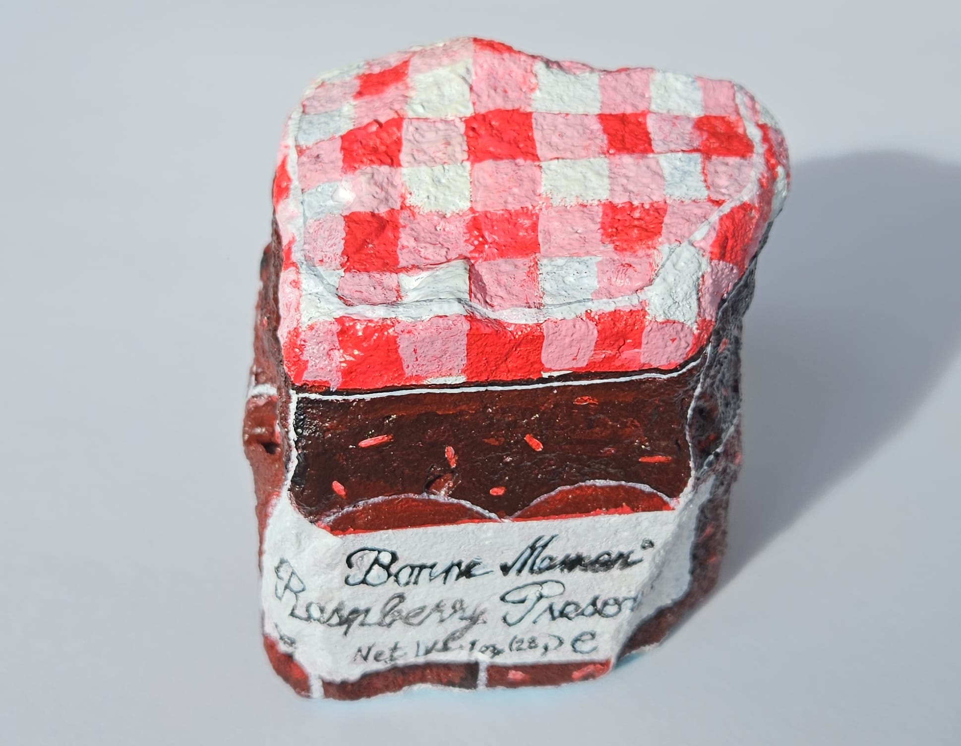 A painted rock by Elizabeth Saloka that resembles a Bonne Maman jam jar