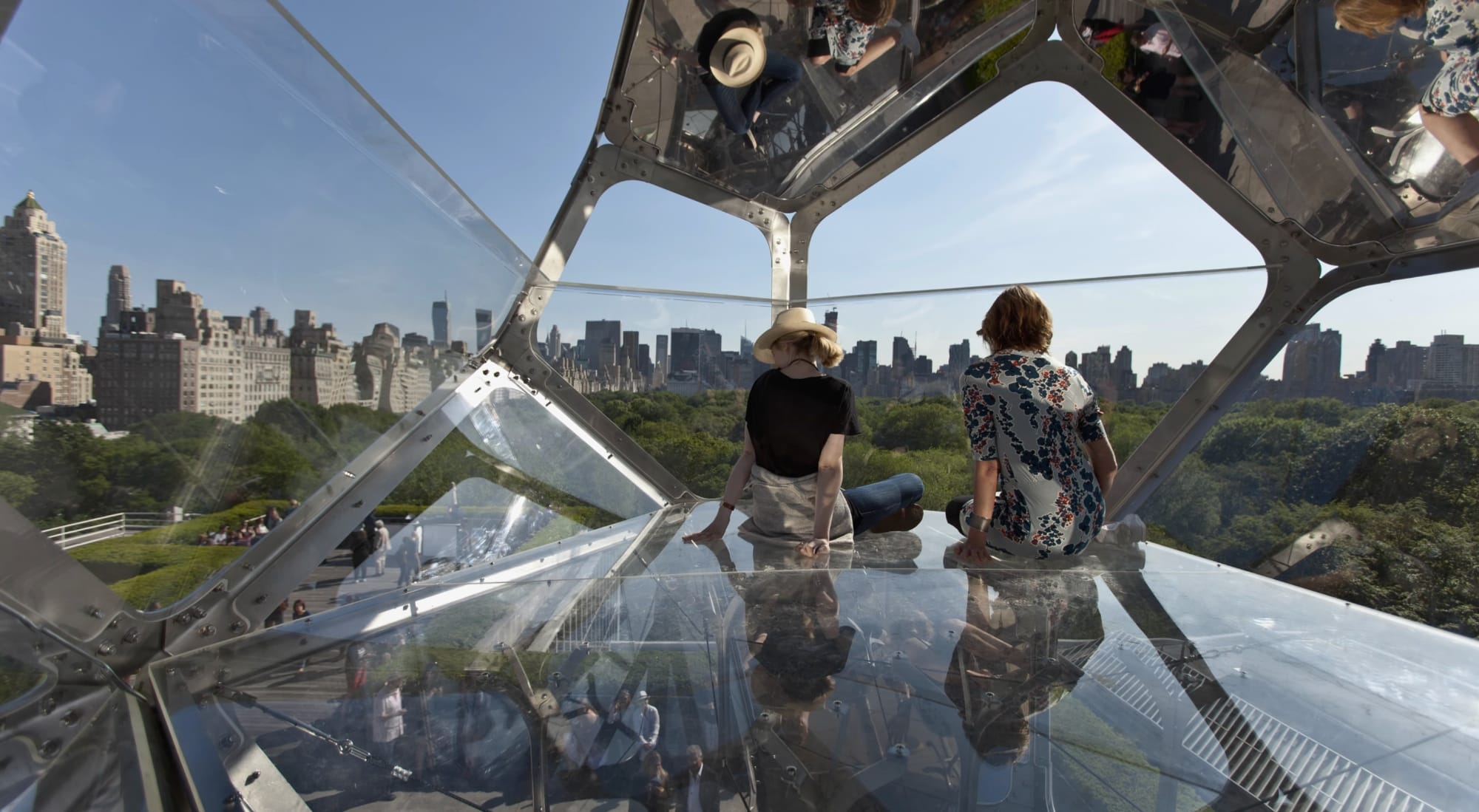 a film still of people sitting in a tall tomas saraceno installation