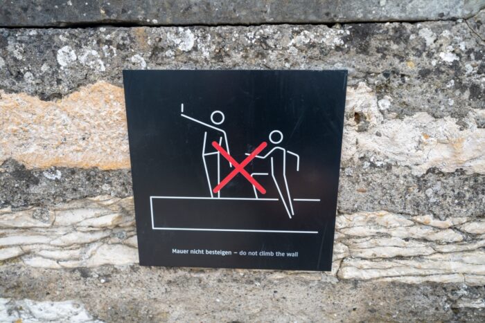 A sign on a wall to prevent people from climbing on walls to take a selfie