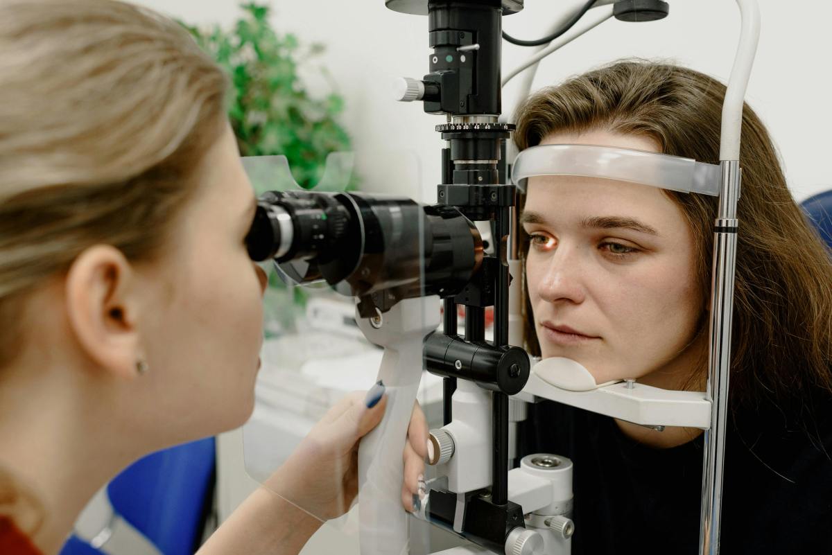 An eye doctor examines a woman's eyes using a slit lamp biomicroscope during an eye check-up.