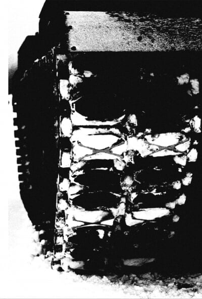 Black and white scanned image of tank treads in the snow.