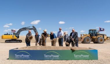 Seven people shovel dirt at a ceremonial groundbreaking.