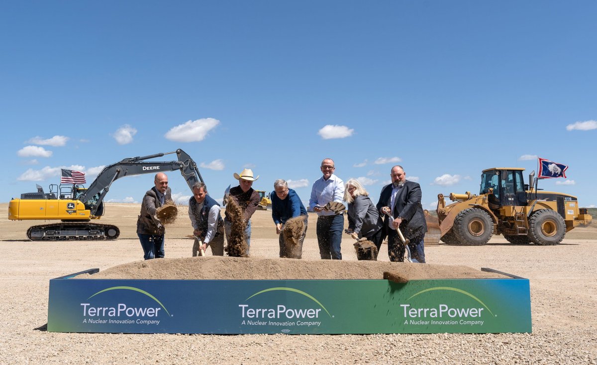 Seven people shovel dirt at a ceremonial groundbreaking.