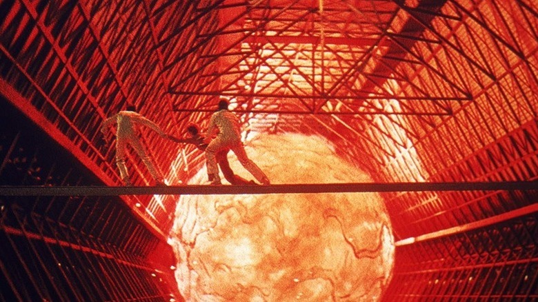 Three characters clad in white run across a walkway in front of a fiery orb in The Black Hole (1979)