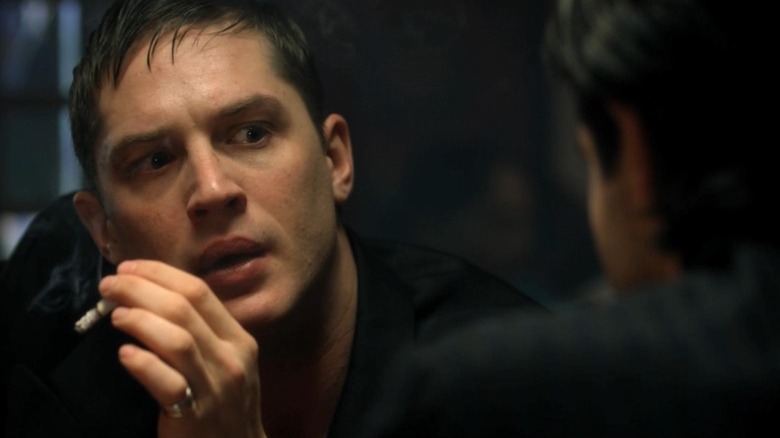 Tom Hardy as Freddie Jackson smoking a cigarette and looking concerned in The Take