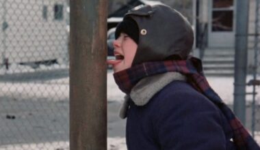 young boy in winter gear, hat and scarf with his tongue sticking out and frozen to a metal pole