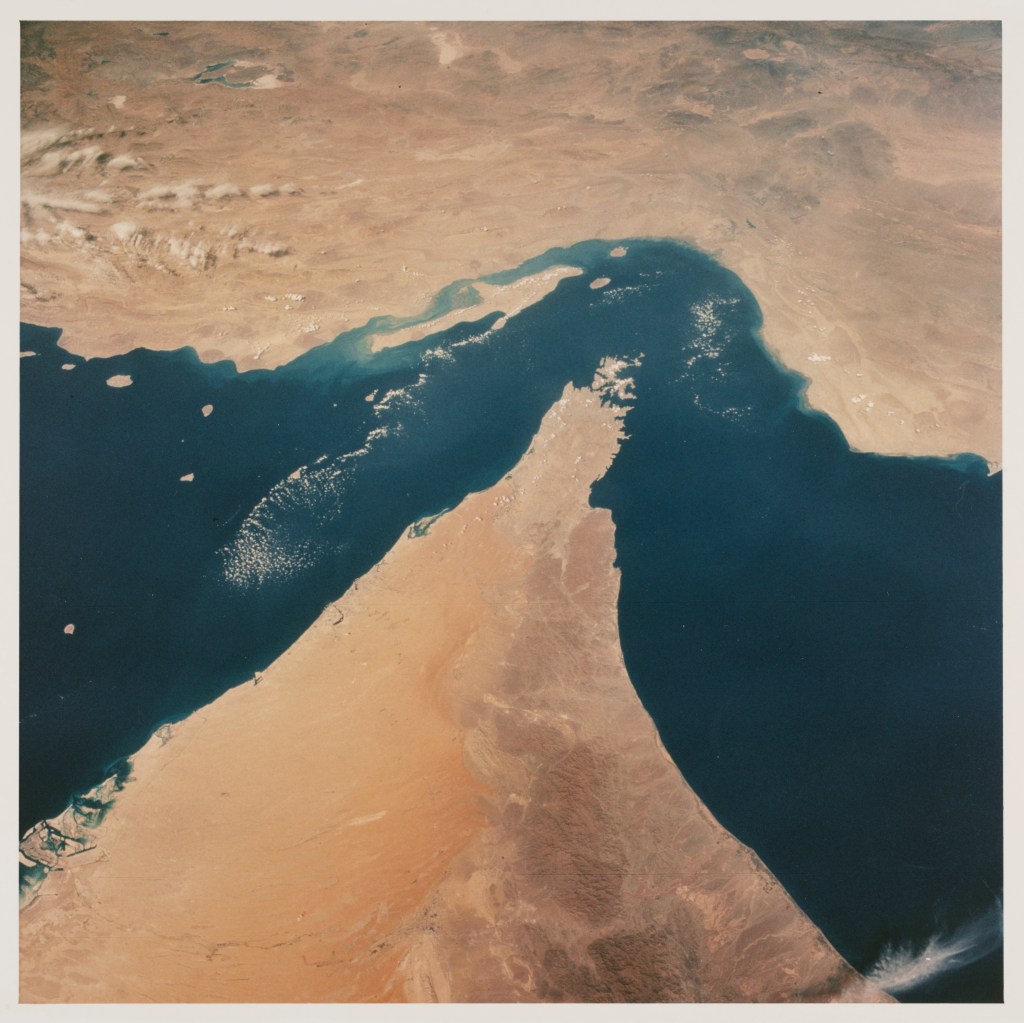 View looking north showing the Strait of Hormuz, connecting the Gulf of Oman with the Persian Gulf, with the Zagros Mountains and Qeshm Island of Iran in the background, and areas of Oman, Muscat and the United Arab Emirates in the foreground