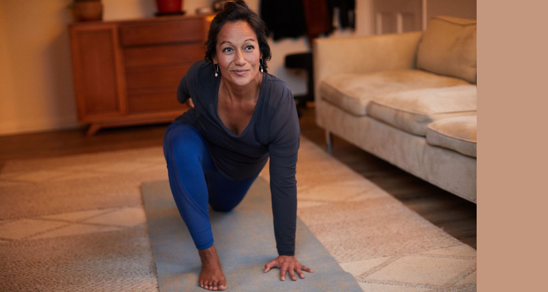 Woman doing 15-minute Pilates workout on yoga mat in living room
