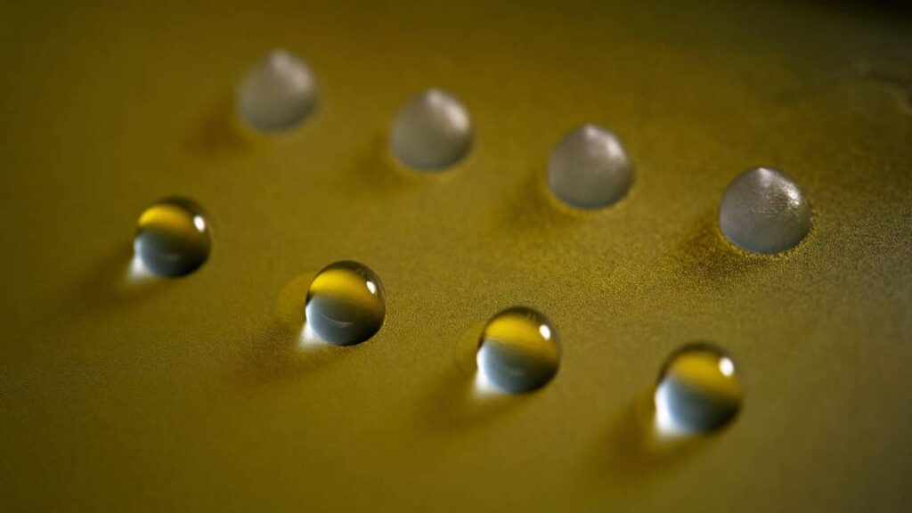 A gold surface with liquid and frozen water droplets 