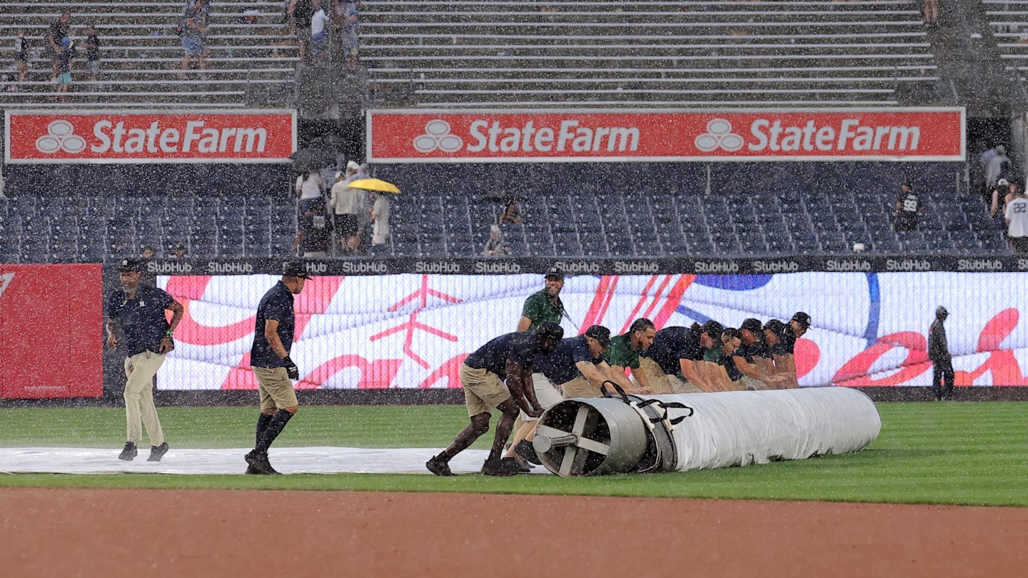 Jul 31, 2025; Bronx, New York, USA; Yankee Stadium grounds crew rolls the tarp onto the infield during a rain delay during the fifth inning between the New York Yankees and the Tampa Bay Rays at Yankee Stadium. Mandatory Credit: Brad Penner-Imagn Images