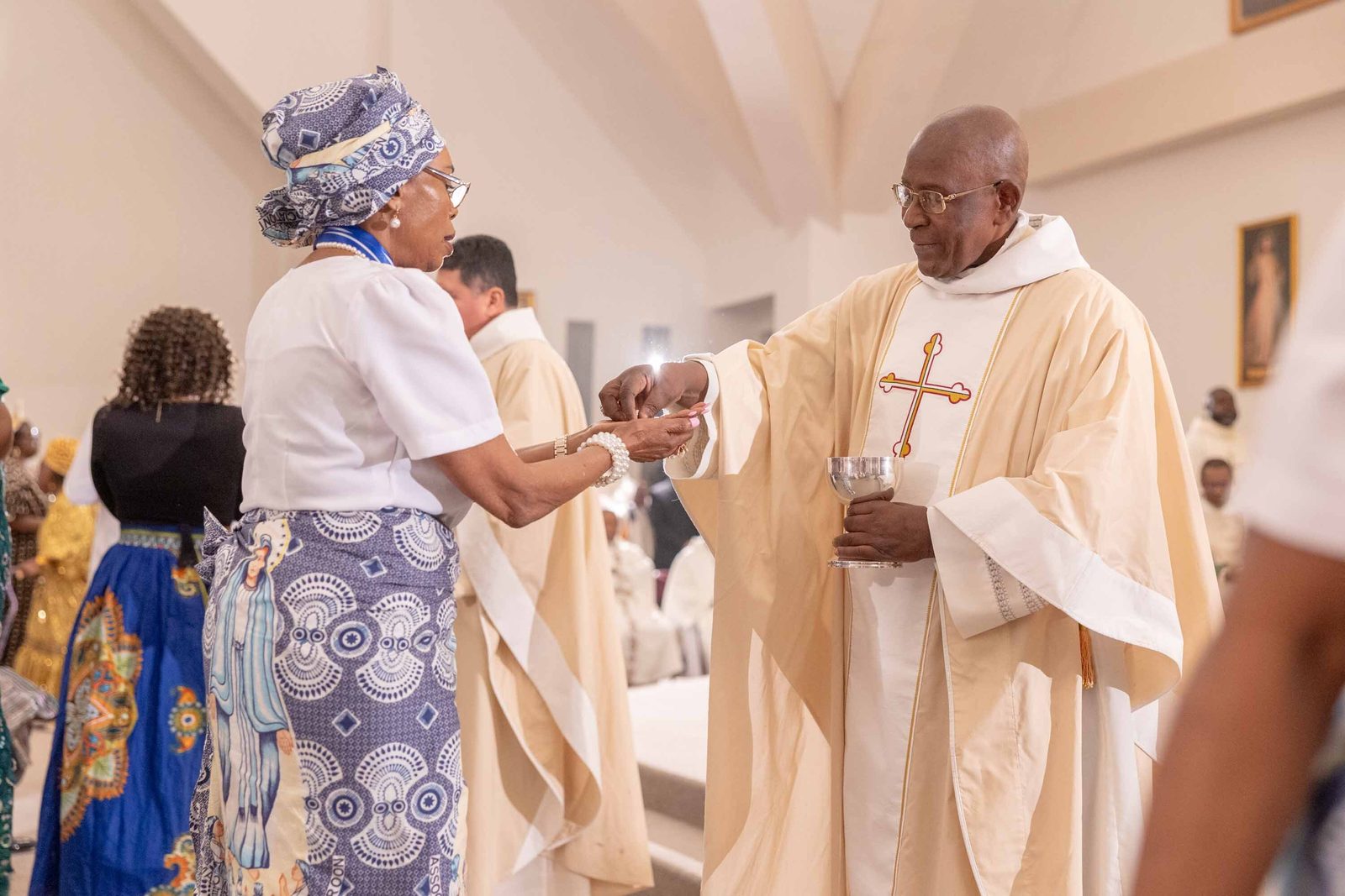 A woman receives Communion from Bishop Jerome Feudjio of the Diocese of St. Thomas in the U.S. Virgin Islands during a Mass of Thanksgiving at St. Joseph Catholic Church in Beltsville, Maryland, on April 17, 2026 that commemorated the bishop’s 70th birthday and his fifth anniversary leading that diocese. (Catholic Standard photo by Mihoko Owada)